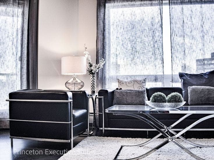 A furnished bedroom in an Edmonton rental suite, with a bed, nightstand, and wardrobe included as part of the tenancy